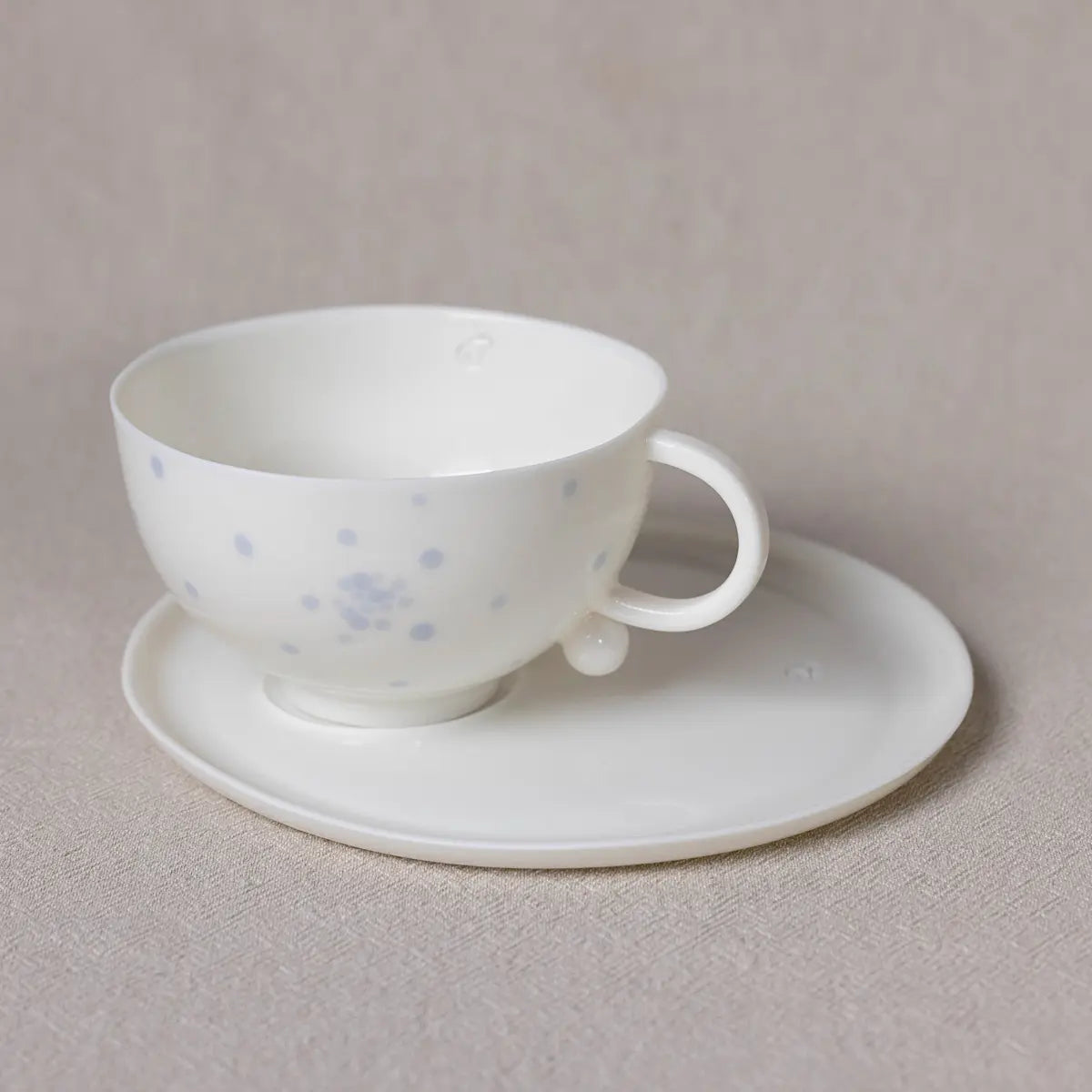  Soulmates Cups" with a handle and blue dot pattern is displayed on an optional saucer against a neutral background.