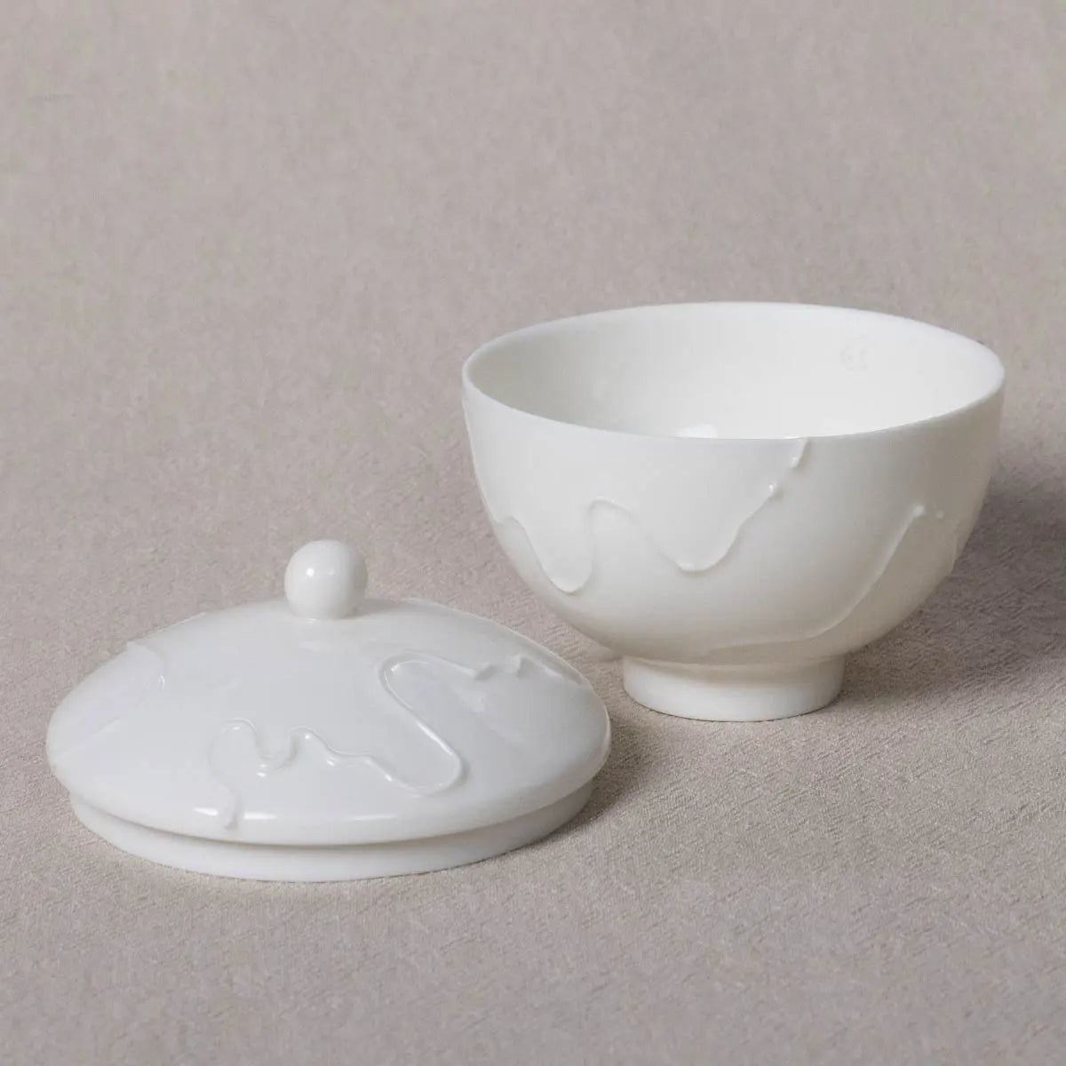 The Sugar Bowl Vida from Urchic Porcelain is a beautifully designed piece with a lid that showcases an elegant swirling pattern against a light-colored background. The lid is conveniently positioned next to the palm-sized bowl, making it both easy to handle and versatile for various uses.