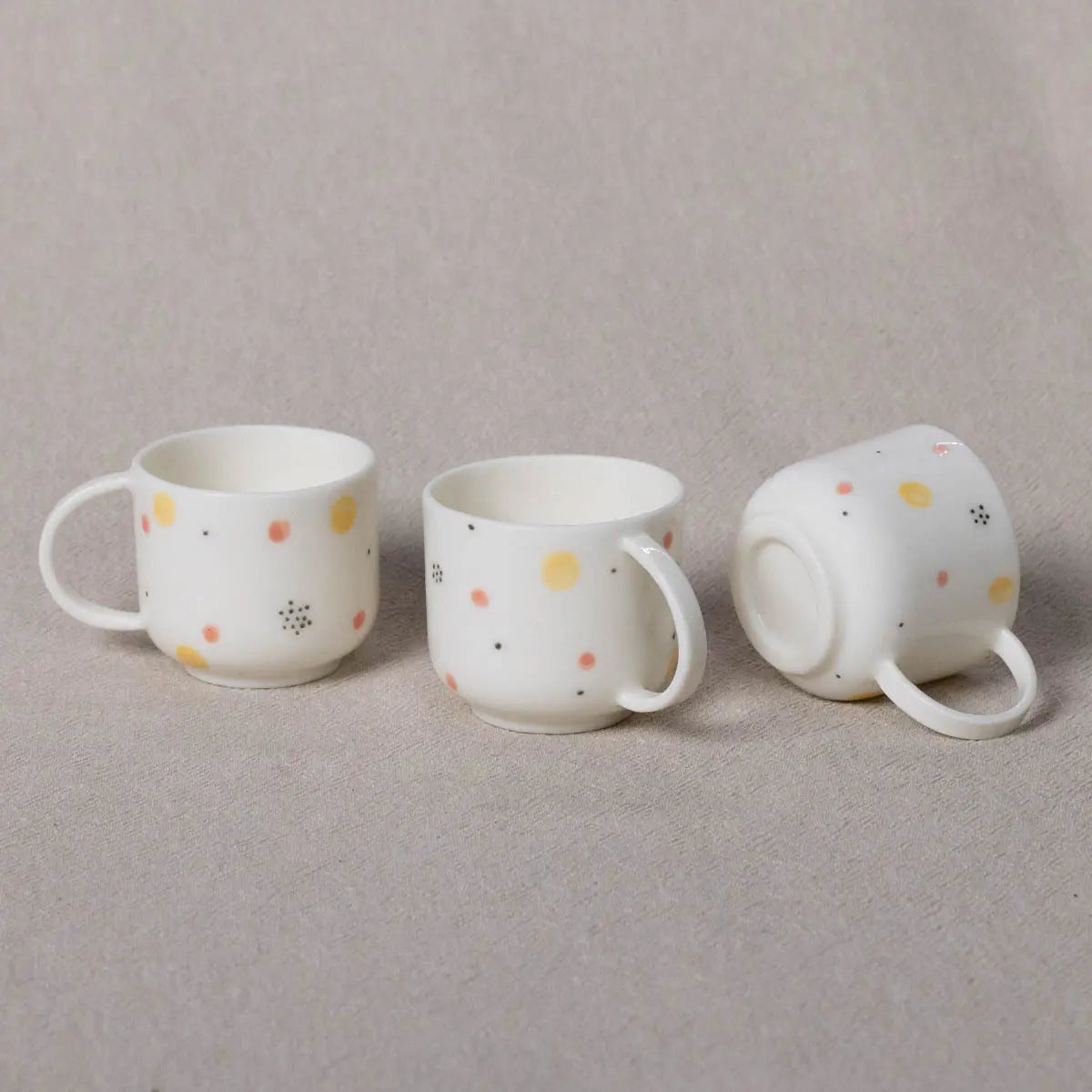 Three Urchic Porcelain Esspreso Mini Cups featuring the Fireworks pattern; two are upright and one is lying on its side, perfect for those special coffee moments. Each cup looks like a charming hand-painted espresso mug, adding a touch of whimsy to your table setting.