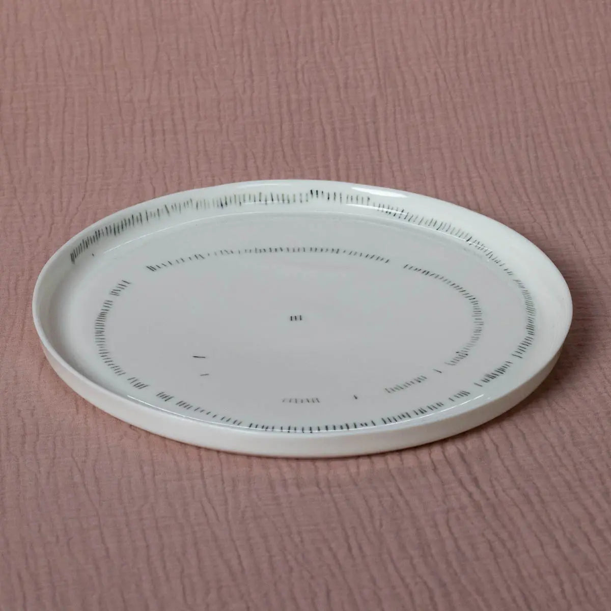 A TRDINKA dinner plate with a Corn fields pattern around the rim, from Urchic Porcelain, placed on a pink textured surface.