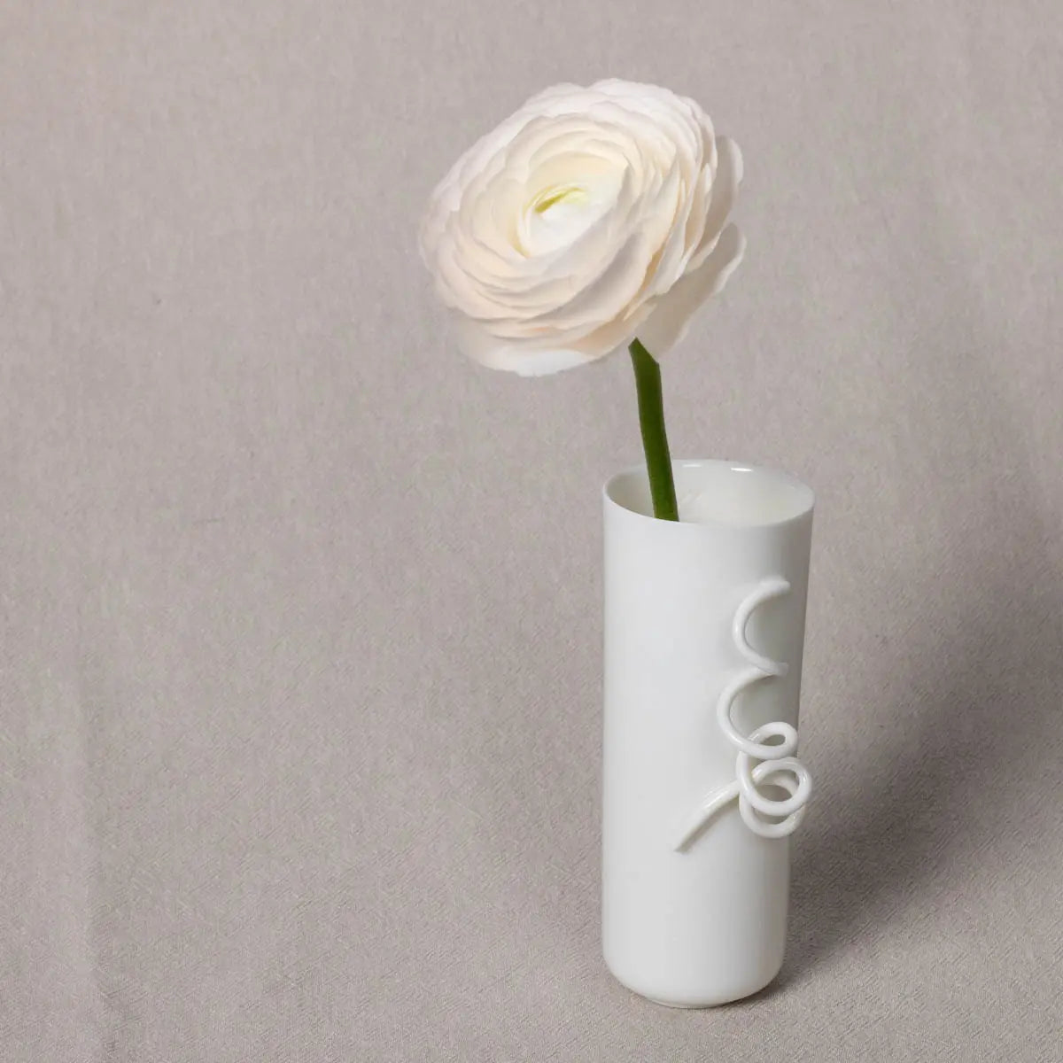 A single white flower in the elegant Vase Kiki with its SPECIAL curly tendril by Urchic Porcelain, set against a plain background.