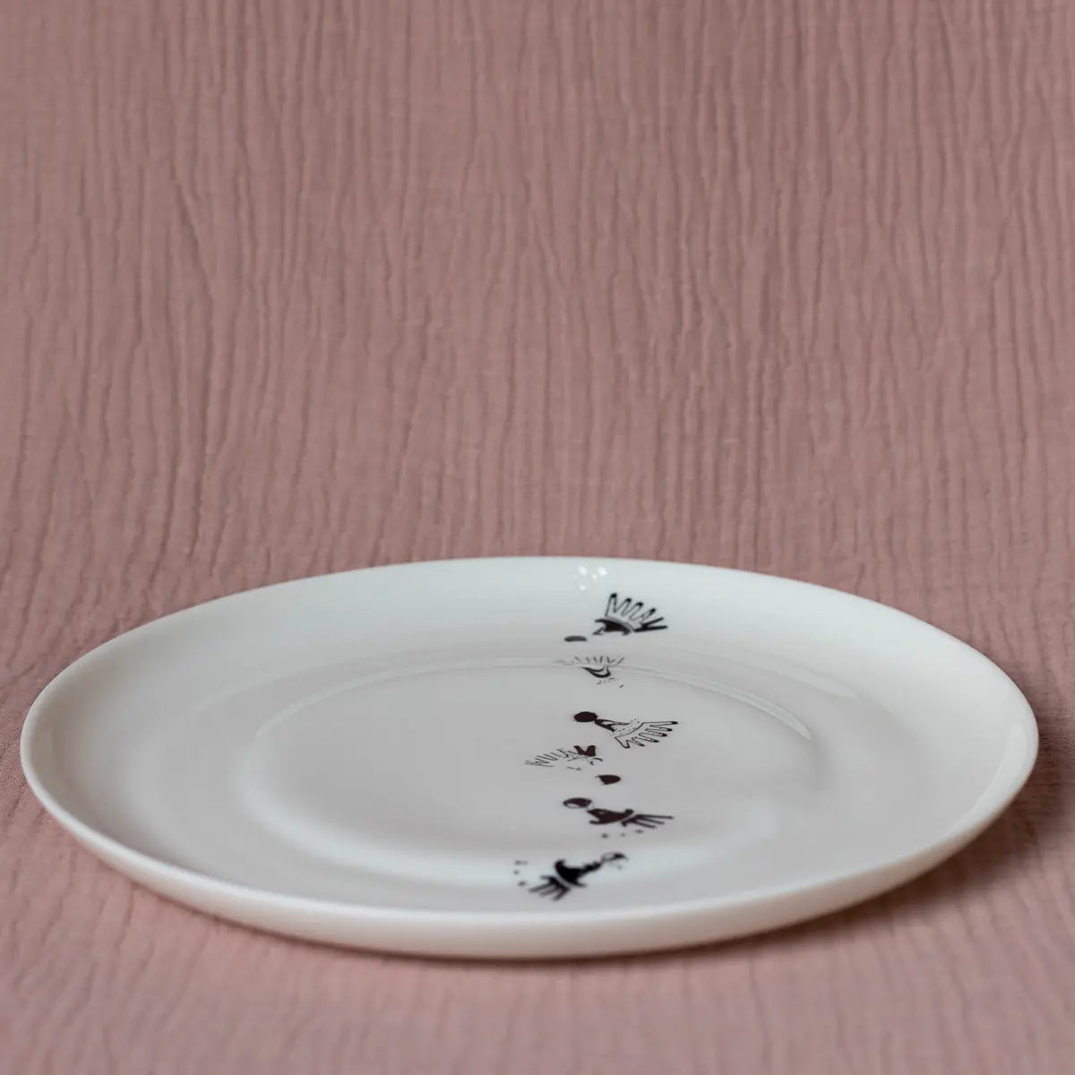 The Vurnik Carnation pattern dinner plate set by Urchic Porcelain, featuring a simplistic design of black birds in flight against a textured, light pink background, stands out as an elegant piece in any dinnerware collection.