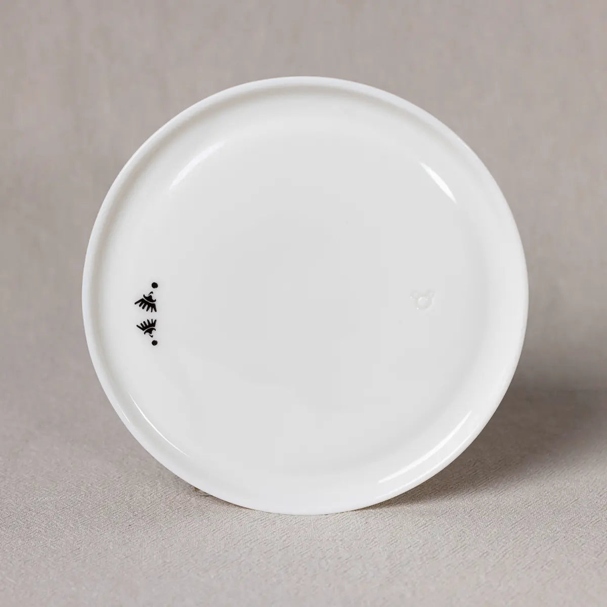 A white round ceramic plate from Urchic Porcelain, named the Breakfast or Dinner Plate with Vurnik Carnation pattern, designed by Rebeka Mamič and featuring a delicate black & white carnation motif on one edge, placed against a neutral background.