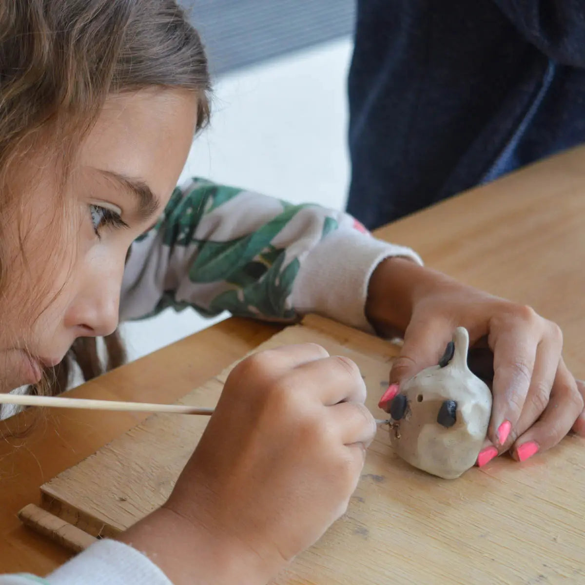 At "GLINARIJE NA LONTRGU: Poletna mala šola gline za otroke – AKONTACIJA" by Urchic Porcelain, kids develop fine motor skills and creativity while crafting clay sculptures during a summer pottery workshop.