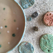 GLINARIJE NA LONTRGU: Poletna mala šola gline za otroke – AKONTACIJA by Urchic Porcelain features handmade ceramic pieces and playful dice-like accents, perfect for sparking children's creativity at a summer pottery workshop.