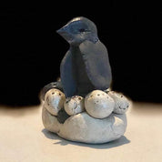 Urchic Porcelain’s "GLINARIJE NA LONTRGU: Poletna mala šola gline za otroke - AKONTACIJA" features a dark bird sculpture on a nest of white eggs and stones, displaying children’s creative skills on a plain background.