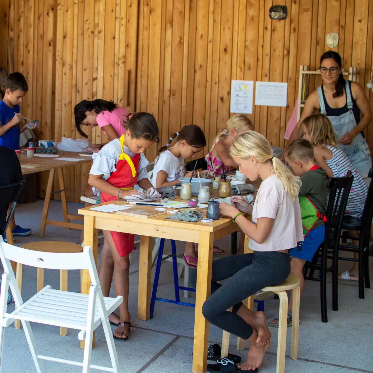 Children engage in creative clay crafts, guided by an instructor, at GLINARIJE NA LONTRGU: Poletna mala šola gline za otroke - AKONTACIJA by Urchic Porcelain—fostering fine motor skills and imagination.