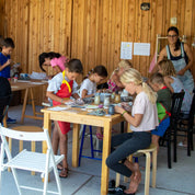 Children engage in creative clay crafts, guided by an instructor, at GLINARIJE NA LONTRGU: Poletna mala šola gline za otroke - AKONTACIJA by Urchic Porcelain—fostering fine motor skills and imagination.